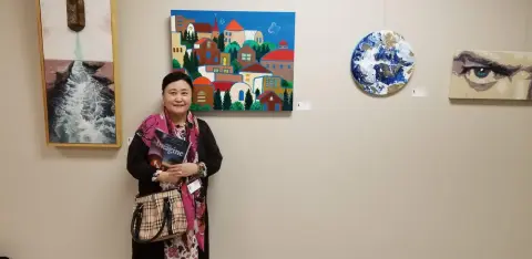 Kristin Sue Kim standing with artwork at an Austin gallery exhibition